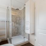 Dusche mit Glaswand, Heizung und Schrank