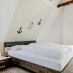 Schlafzimmer mit Doppelbett, Ankerdekoration und Fenster.