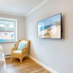 Bedroom with bed, chair, and TV mounted on the wall.