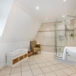 Bathroom with shower, sink and toilet under sloped ceiling.