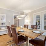 Dining room with wooden table, six chairs, and pendant light.