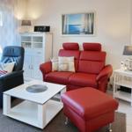 Red sofa with footstool, black armchair, white coffee table, and wall art.