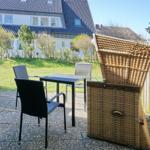 Terrace with table, chairs, and lounge chair. Background: house and garden.
