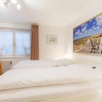 Bedroom with double bed, window, and wall picture.