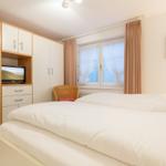 Bedroom with double bed, TV, and window with curtains.