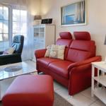 A living room with red sofa, black chair and glass table.