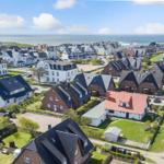 Aerial view of coastal village with houses and sea in background.