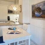 Dining area with table, chairs, and kitchen in the background.