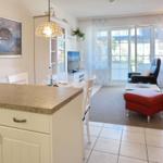 Kitchen with dining area and living room with red armchair and TV.