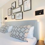 Schlafzimmer mit Bett, Wandbildern und Nachttischlampe.