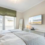 Schlafzimmer mit Bett, Fenster, Spiegel und Wandbild.