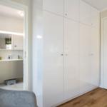 Schlafzimmer mit weißem Schrank und Blick in das Bad.