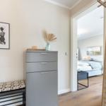 Schlafzimmer mit Kleiderschrank, Wandbild und Holzstange. Blick in Schlafbereich mit Bett und Nachttisch.