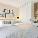 Schlafzimmer mit Bett, Wandbildern und Schminktisch mit Spiegel.