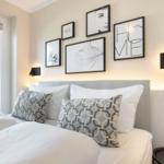 Schlafzimmer mit Bett, Wandbildern und Fenster. Beleuchtung an der Wand.