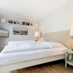 Schlafzimmer mit Bett, Nachttisch und Wandregalen.