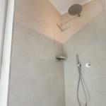 Dusche mit Duschbrause und Handbrause, Wandfliesen und Fenster.