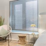 Schlafzimmer mit Bett, Stuhl und Fenster mit Jalousie.