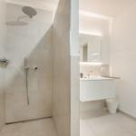 Dusche mit Duschbrause und Waschbecken mit Spiegel