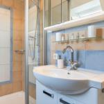 Badezimmer mit Dusche, Waschbecken und Spiegel