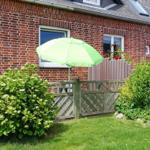 Rotes Backsteinhaus mit grünem Sonnenschirm und gepflegtem Garten.