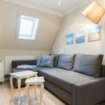 Wohnzimmer mit grauem Sofa, weißen Tischen und Fenster