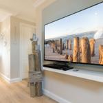 Großer Fernseher mit Strandbild, Holzpfosten-Dekoration und heller Holzboden