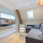 Wohnzimmer mit Sofa, Fernseher und Dachfenster.