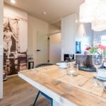 Esszimmer mit Holztisch, Stühlen und Blumendekoration.
