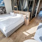 Schlafzimmer mit Doppelbett, Holzboden und Strandbild an der Wand.