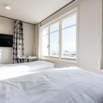 Zimmer mit Doppelbett, TV und Blick aufs Meer.