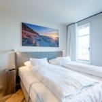 Schlafzimmer mit Doppelbett, Wandbild und Fenster.