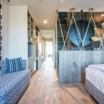Schlafzimmer mit Bett, Sitzbank und moderner Dusche.