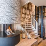 Moderne Wohnfläche mit Kamin, Holztreppe und Glaslift.