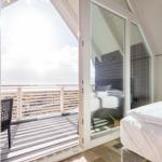 Schlafzimmer mit Balkon und Meerblick durch große Glasschiebetüren.