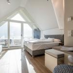 Schlafzimmer mit Doppelbett, großem Fenster und Holzboden.