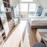 Schlafzimmer mit Doppelbett, Balkon und Holzboden.