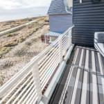Terrasse mit Sitzgelegenheit und Meerblick. Holzdeck und weißer Geländer.