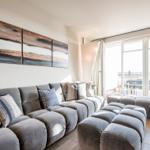 Großer Wohnbereich mit grauem Sofa und moderner Wanddekoration.