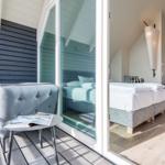 Terrasse mit Sitzgelegenheit und Blick in das Schlafzimmer mit Bett und Lampen.