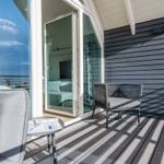 Terrasse mit Sitzgelegenheit und Meerblick durch Glasfront