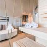 Sauna mit Holzbank und Handtüchern. Im Hintergrund Sofa und Bad.