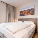 Schlafzimmer mit Doppelbett, Fenster und Wandbild.