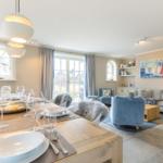 Essbereich mit Tisch und Stühlen, Wohnzimmer mit Sofa und Kissen.