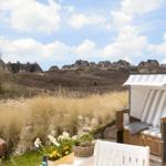 Strandkorb mit Streifenbezug, Blumen und Blick auf Häuser auf Dünen.