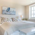 Schlafzimmer mit Bett, Fenster und Wandbild mit Segelbooten.