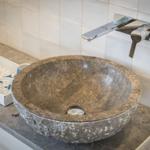 Steinspüle mit modernem Wasserhahn auf Arbeitsfläche