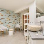 Badezimmer mit Fischtapete, Steinwaschbecken und weißen Möbeln.