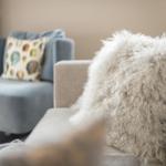 Ein Sofa mit flauschigem Kissen und ein Sessel mit Musterkissen.