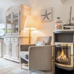 Wohnzimmer mit Kamin, Sessel und Fernseher. Dekoration mit Segelboot und Sternfisch.